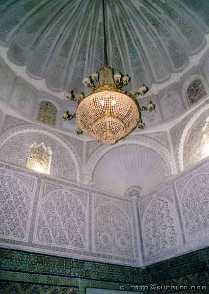 image-046 <p><b>Kairouan</b></p>
<br>
<div align=left>
<p><b>21. September 2003: Kairouan (Barbiermoschee und die Große Moschee), Tataouine</b></p>
<p>Heute Morgen wollte Robin ganz besonders früh mit uns aufbrechen, um nämlich wieder einmal vor den ersten Touristenscharen an Ort und Stelle zu sein. Unser erstes Ziel heute sind die zwei wichtigsten Moscheen in Kairouan, die Barbiermoschee und die Große Moschee.</p>
<p>Ein Local Guide (diesmal einer, der Lust hatte) hat uns geführt. Typisch für die Barbiermoschee sind die bunten Kacheln aus Nabeul. Das Innere der Kuppel ist aus Holz geschnitzt und keines der Muster gleicht dem anderen. Wir durften uns in Ruhe alles anschauen und auch fotografieren, nur den Gebetsraum durften wir als Nichtmoslems nicht betreten.</p>
</div>