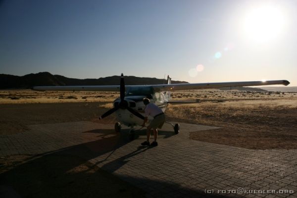 IMG_3796 <P><B>Rundflug über die Namib</B></P>

<div align=left>
<P>Am heutigen Nachmittag haben wir kein festes Programm und erledigen mal Dinge wie Wäsche waschen, duschen, in den Swimmingpool hüpfen und Siesta halten.</P>

<P>Fast die ganze Gruppe hat sich dazu entschlossen, einen Rundflug über die Wüste zu machen und Konrad hat einen guten Preis ausgehandelt. Auf drei Flüge aufgeteilt fahren wir zum nahe gelegenen Airstrip.</P>

<P>Wie die Ölsardinen quetschen wir uns in den Rumpf der kleinen fünfsitzigen Cessna und heben von der Schotterpiste ab. Der Wind rüttelt kräftig an dem kleinen Flieger und die Luftlöcher machen den Flug zum Achterbahnerlebnis - ein Riesenspaß.</P>
</div>