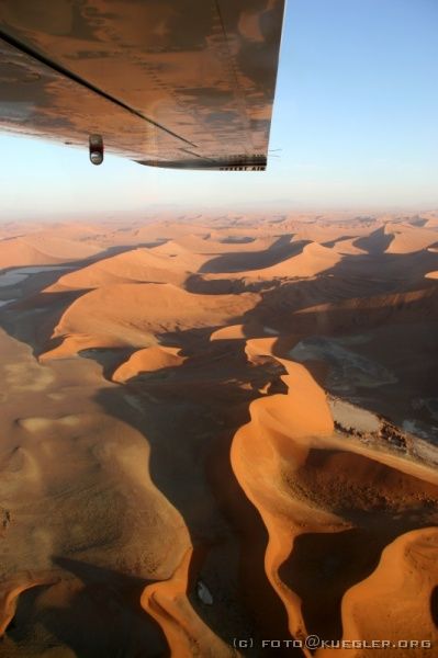 IMG_3880 <P><B>Rundflug über die Namib</B></P>

<div align=left>
<P>Die Sonne steht bereits sehr tief und wirft bizarre Schatten in
das Meer aus Sand, es ist sagenhaft schön. Zum Glück sind
nicht alle Bilder verwackelt. Es ist gar nicht einfach, die Kamera
ruhig zu halten. Wir fliegen über die Dünen bis weit über
das Soussusvlei in die Namib, bis soweit das Auge reicht nur noch
rote Dünen zu sehen sind.</P>
</div>