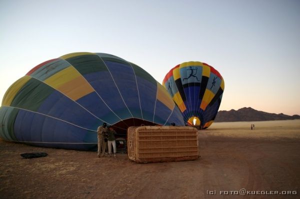 IMG_3912 <P><B>Ballonfahrt</B></P>

<div align=left>
<P><B>23. Oktober: Ballonfahrt und Weiterfahrt nach Swakopmund</B></P>

<P>Heute ist es soweit, der lang gehegte Wunsch einer Ballonfahrt geht in Erfüllung.</P>

<P>Dieses mal ist unsere Nacht bereits um 4.00 Uhr zu ende, denn Robson lässt den Motor an. Er muss eine andere Gruppe seiner Agentur abholen, deren Truck liegen geblieben ist und sie zur Düne 45 und ins Soussusvlei bringen.</P>

<P>Um 4.45 Uhr ist für uns sowieso Zeit zum Aufstehen, denn wir müssen unsere Sachen gepackt hinterlassen, damit es nach unserer Ballonfahrt gleich losgehen kann. Am Tor des Nationalparks werden wir vier von einem Jeep abgeholt und zu den Ballons gefahren, die auf dem
Gelände einer etwa 30km entfernten Farm starten.</P>
</div>