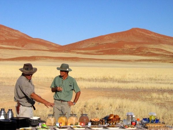 IMG_6648 <P><B>Nach der Ballonfahrt</B></P>

<div align=left>
<P>Es gibt Sekt, Kaffee, Croissants, selbst gebackenes Brot, Zebraschinken, Butterfisch... und das Ganze mit Blick auf die von der Morgensonne rot gefärbten Dünen der Namib - vielleicht ein bisschen dekadent, aber schön.</P>

<P>Als es zum Aufbruch geht und alle wieder in die Jeeps steigen, landen wir in einem dunkelblauen Wagen mit getönten Scheiben und dachten schon: Hmmm... Air Condition! Aber keine Minute später sind wir schon wieder draußen. Sesriem Camp oder Soussusvlei Lodge? Camp. Dann müssen Sie in den offenen Jeep. Klar, wir hatten ja nur Economy gebucht!</P>
</div>